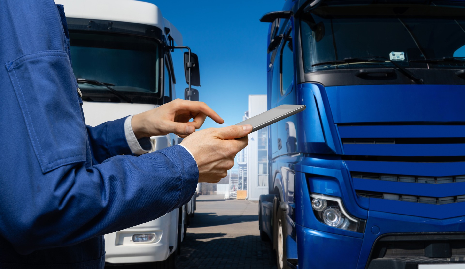 Fleet manager with digital tablet on a background of trucks.